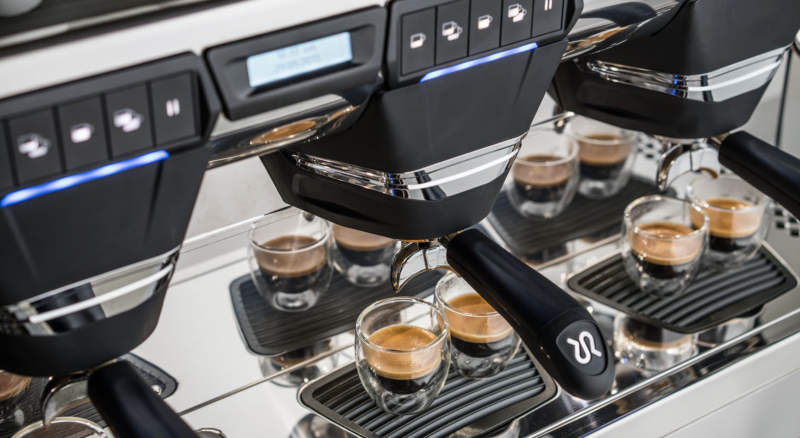 This image is a closeup front view of the Rancilio Classe 7 espresso machine brew groups, with traditional brew group and USB Volumetric Dosing Controls.